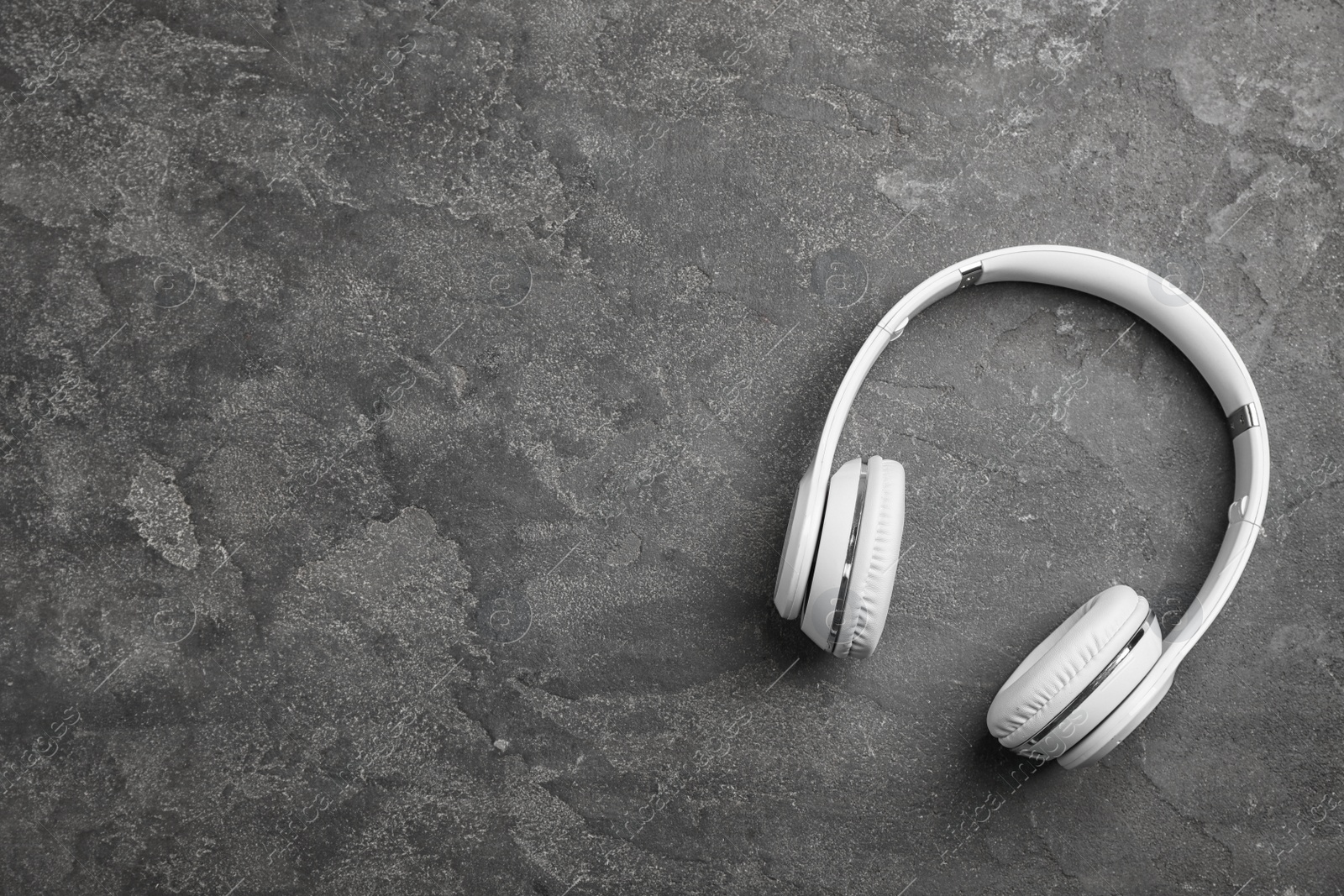 Photo of Stylish modern headphones and space for text on concrete background, top view