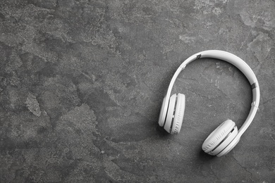 Photo of Stylish modern headphones and space for text on concrete background, top view