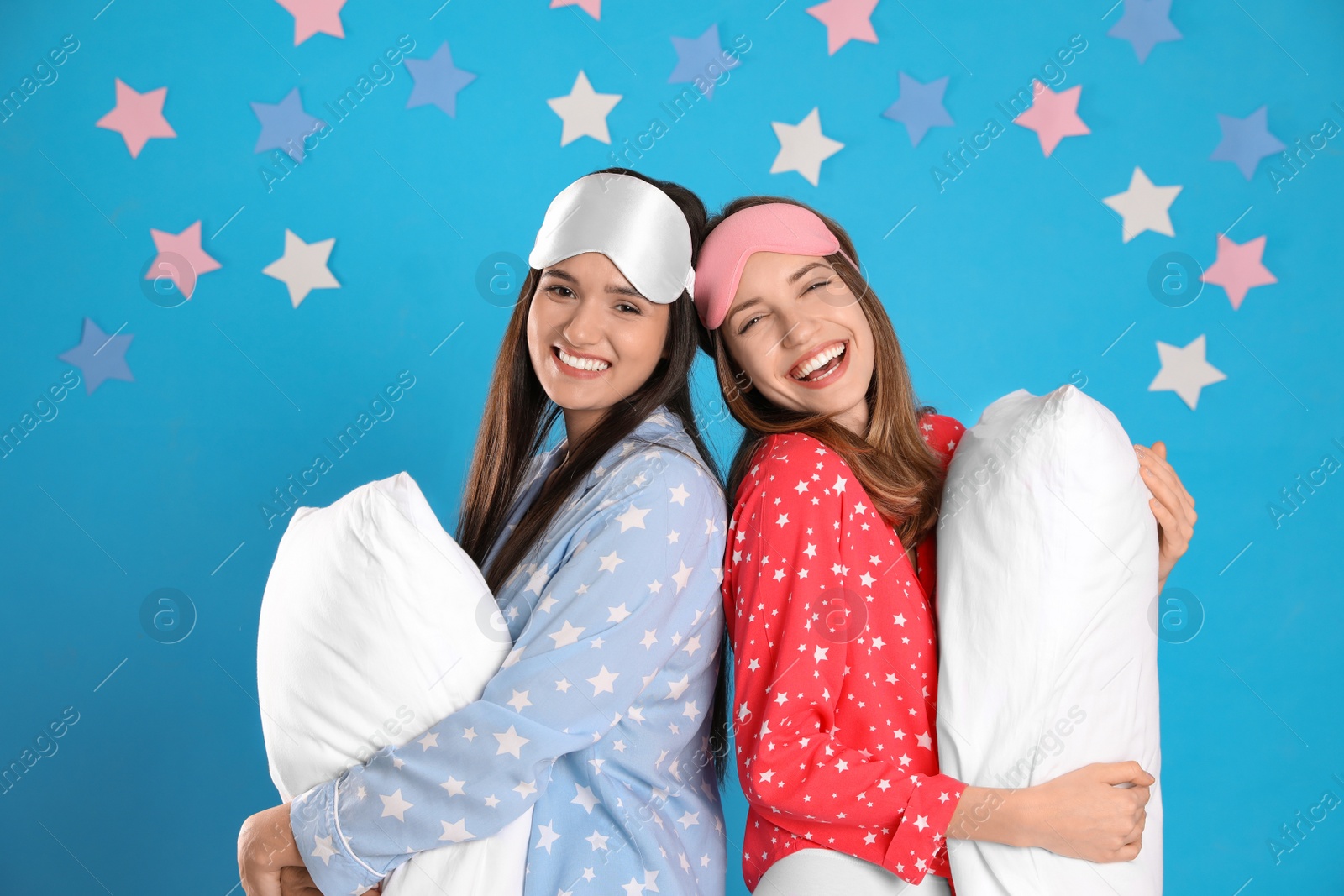 Photo of Beautiful women with pillows on light blue background. Bedtime