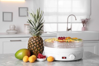 Photo of Fruits and dehydrator machine on grey marble table in kitchen