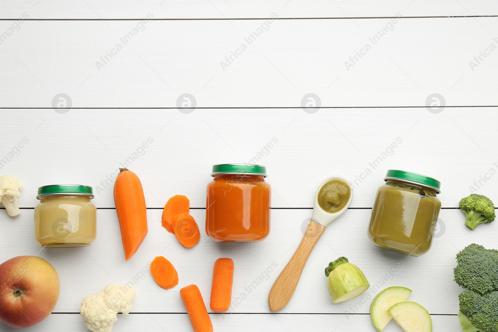 Photo of Flat lay composition with tasty baby food in jars and ingredients on white wooden table. Space for text