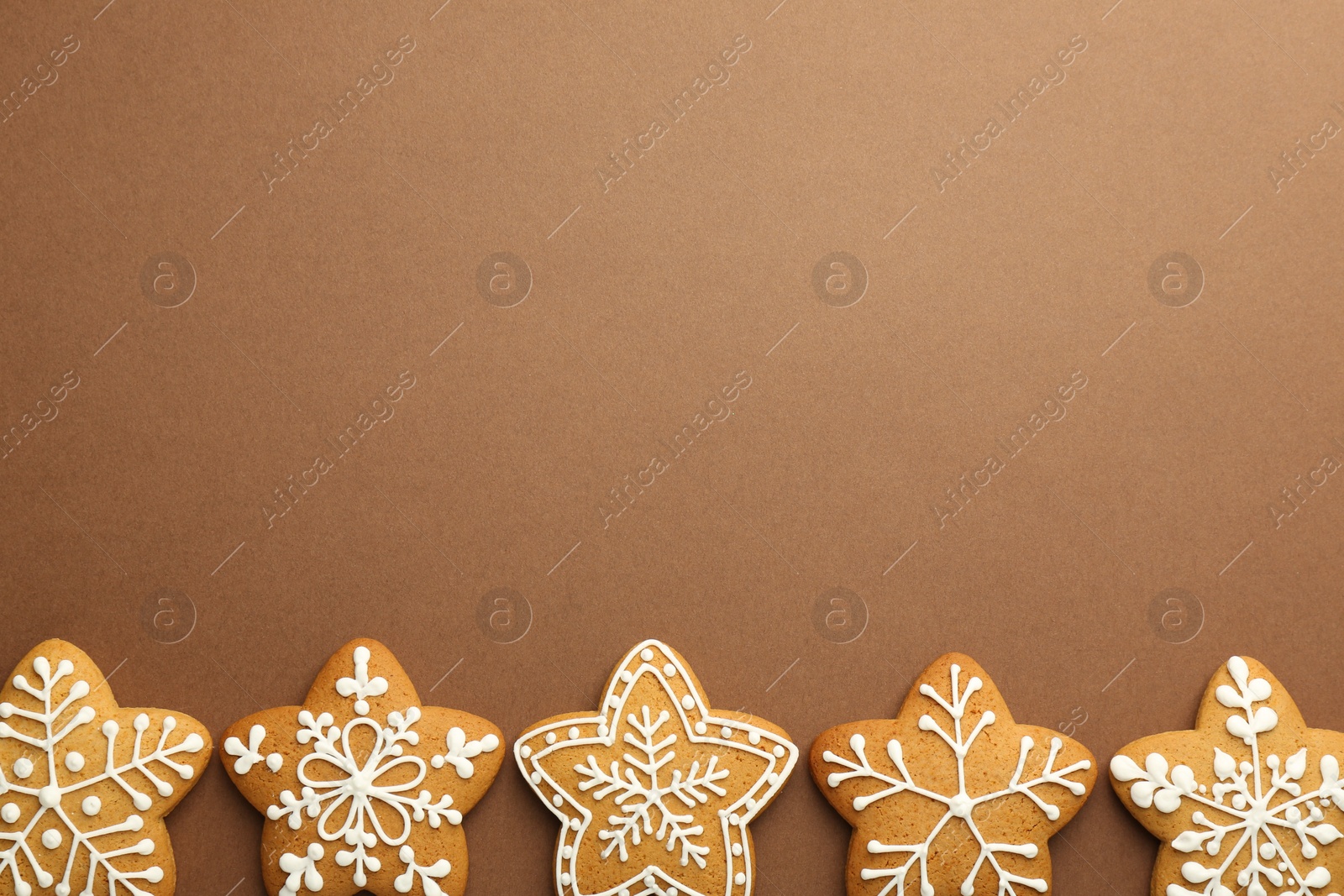 Photo of Tasty Christmas cookies with icing on brown background, flat lay. Space for text