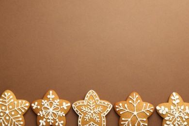 Photo of Tasty Christmas cookies with icing on brown background, flat lay. Space for text