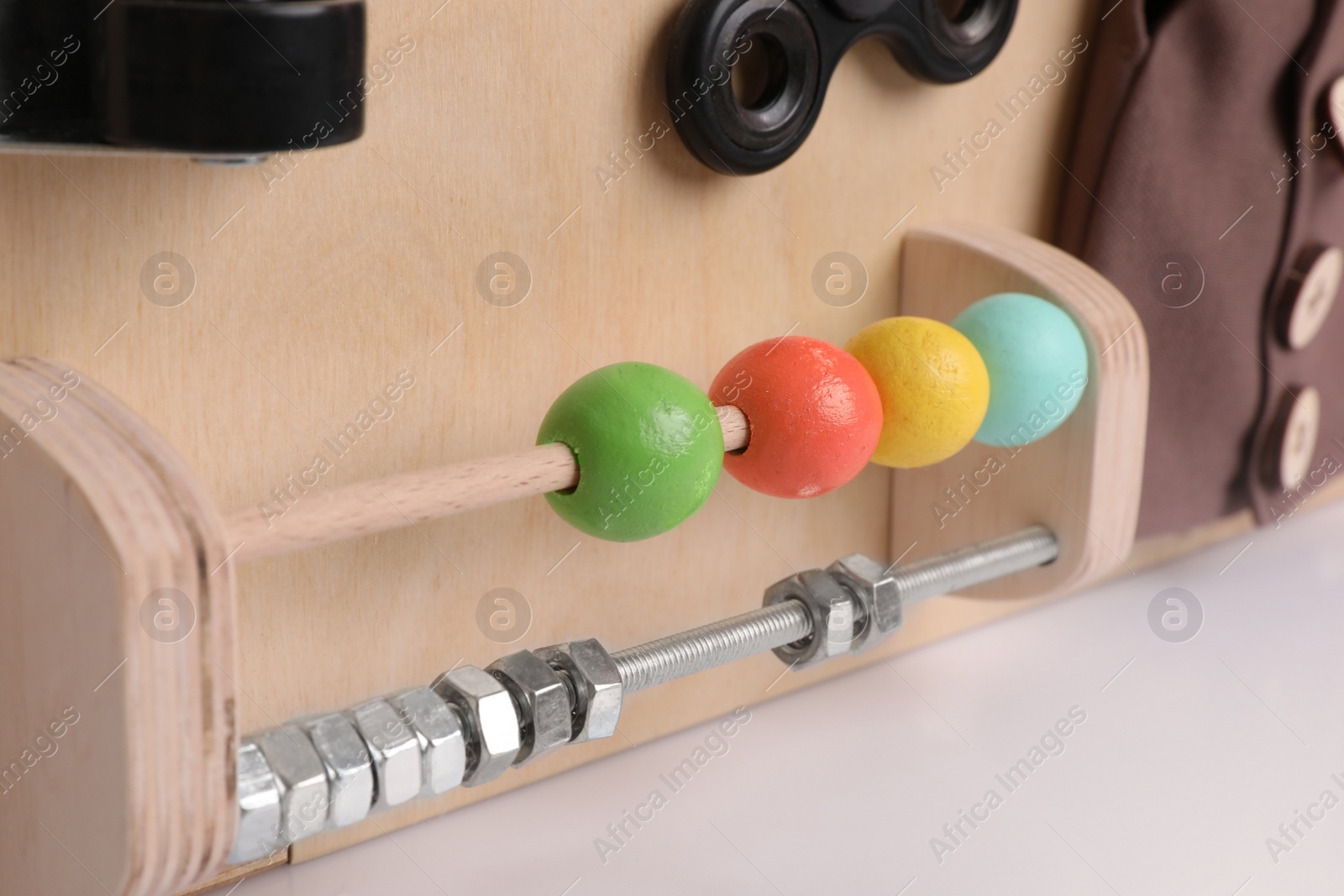 Photo of Closeup view of busy board on white background. Baby sensory toy