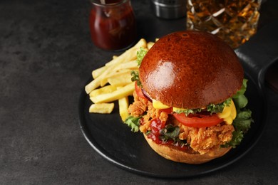 Photo of Delicious burger with crispy chicken patty and french fries on black table