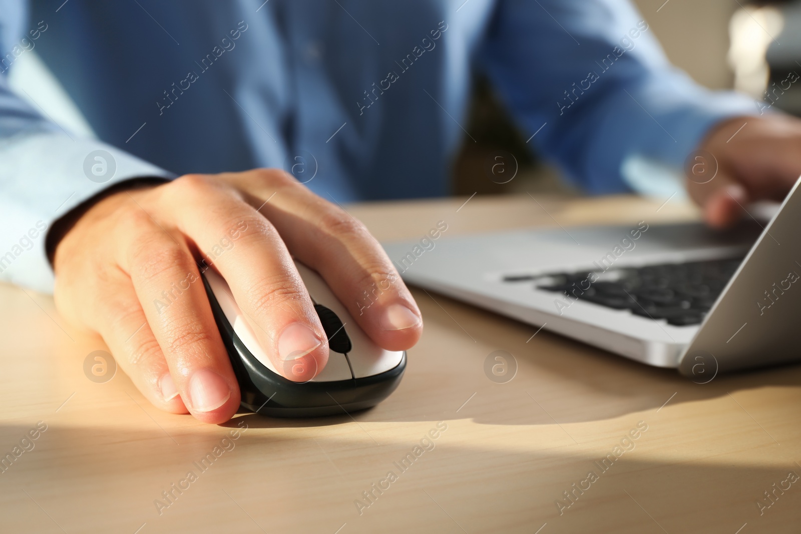 Photo of Man using computer mouse with laptop at table, closeup