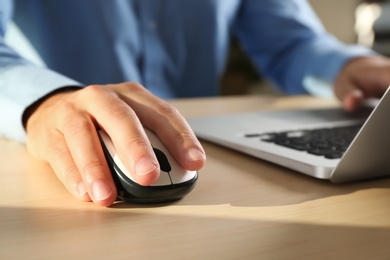 Photo of Man using computer mouse with laptop at table, closeup