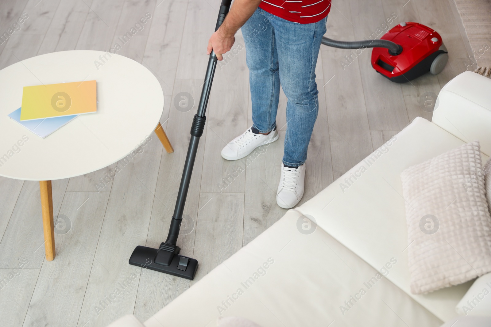 Photo of Young man using vacuum cleaner at home, closeup