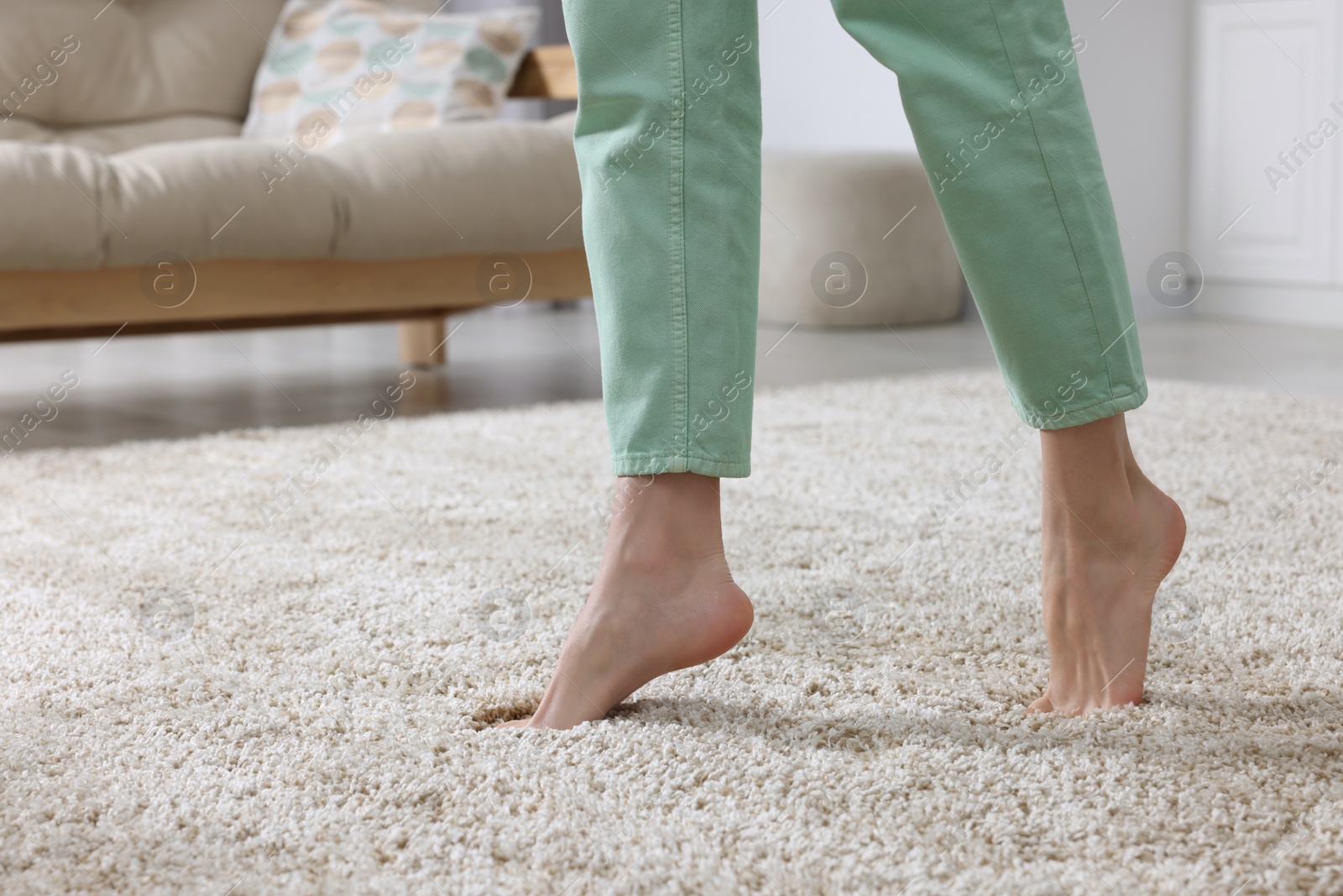 Photo of Woman walking on soft beige carpet at home, closeup. Space for text