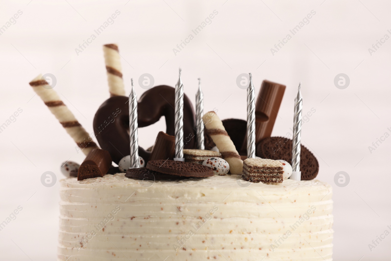 Photo of Delicious cake decorated with sweets and candles against blurred background, closeup