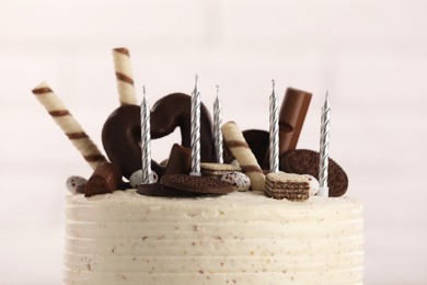 Photo of Delicious cake decorated with sweets and candles against blurred background, closeup