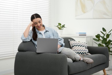 Woman using laptop on couch at home