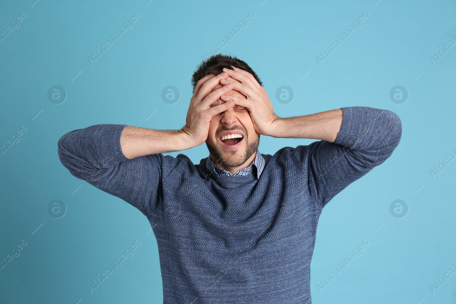 Photo of Man suffering from terrible migraine on light blue background