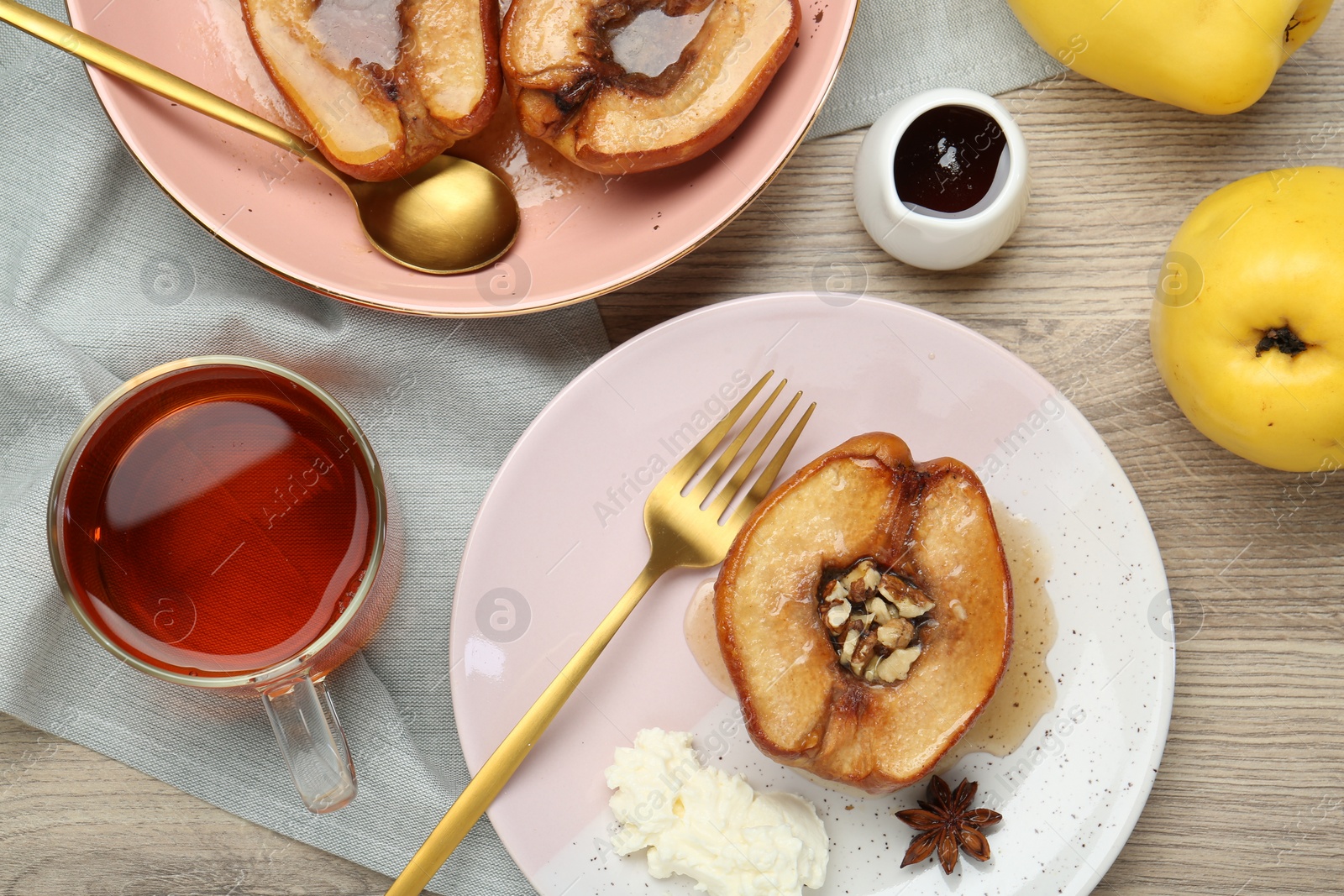 Photo of Delicious quinces baked with honey and walnuts on wooden table, flat lay