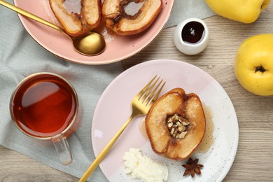 Photo of Delicious quinces baked with honey and walnuts on wooden table, flat lay