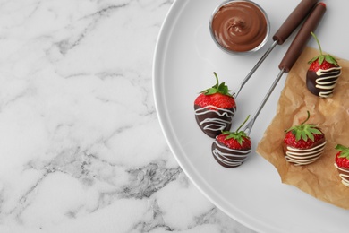 Photo of Plate with chocolate covered strawberries on marble background, top view