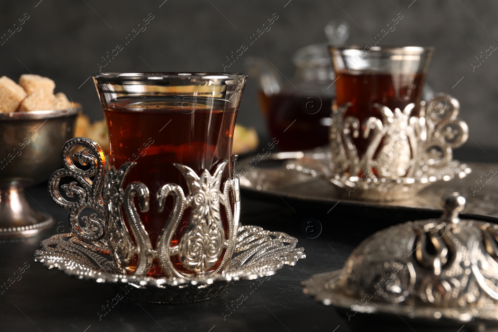 Photo of Traditional Turkish tea served in vintage tea set on black table, closeup