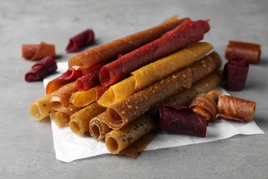 Photo of Delicious fruit leather rolls on grey table