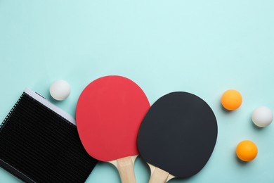 Photo of Ping pong rackets, net and balls on turquoise background, flat lay. Space for text