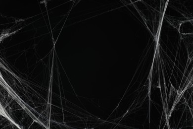 Creepy white cobweb on black background, space for text