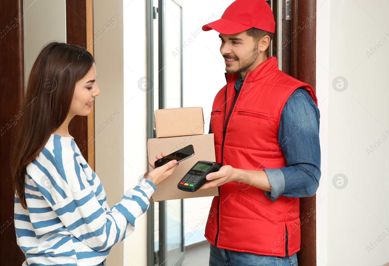 Photo of Young woman with smartphone using terminal for delivery payment indoors