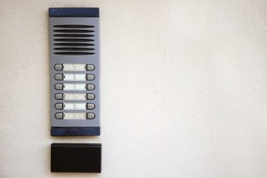 Photo of Modern intercom on beige wall, space for text