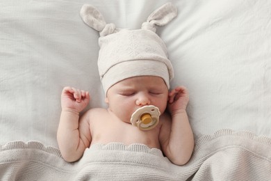 Adorable little baby with pacifier sleeping in bed, top view