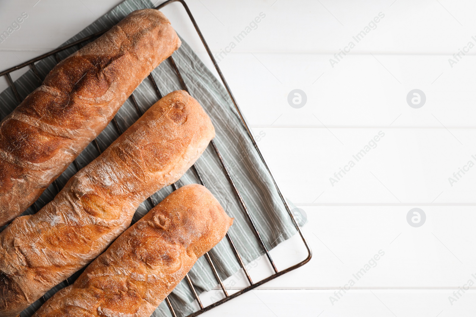 Photo of Fresh crispy ciabattas on white wooden table, top view. Space for text