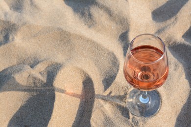 Photo of Glasstasty rose wine on sand, space for text