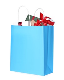 Photo of Light blue paper shopping bag full of gift boxes on white background