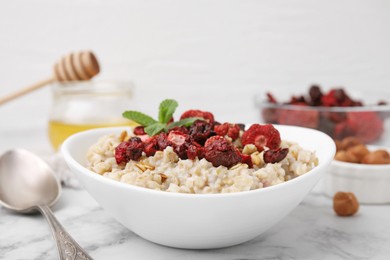 Photo of Oatmeal with freeze dried strawberries and mint on white marble table