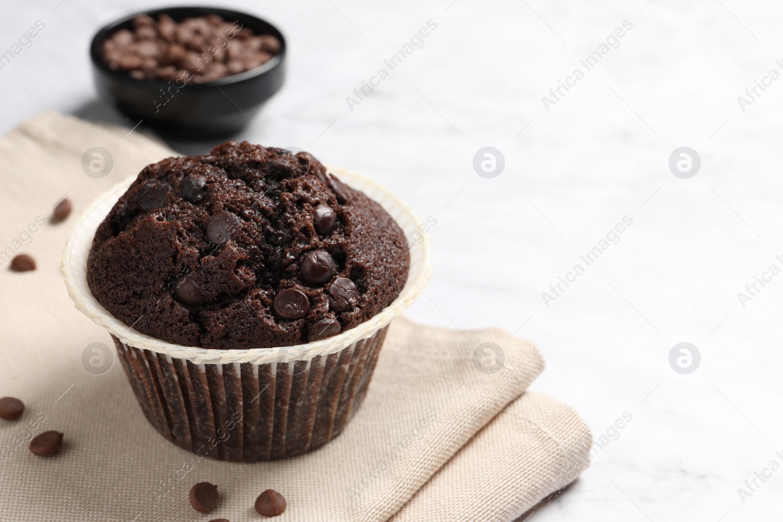 Photo of Tasty chocolate muffin on white table, closeup. Space for text