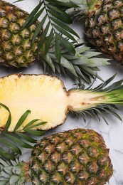 Photo of Whole and cut ripe pineapples on white marble table, flat lay