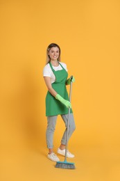 Photo of Young woman with broom on orange background