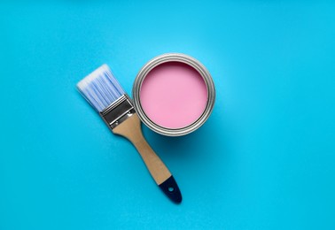 Photo of Can with pink paint and brush on light blue background, flat lay