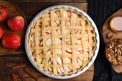 Raw traditional English apple pie and ingredients on wooden table, flat lay