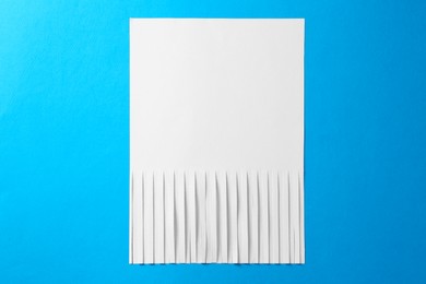 Photo of Half shredded sheet of paper on light blue background, top view