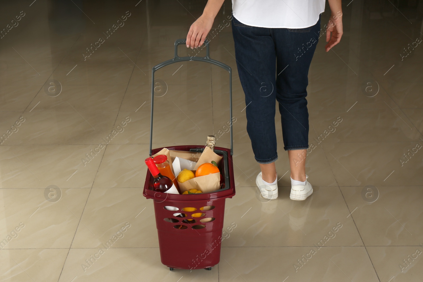 Photo of Woman with shopping basket full of different products, closeup