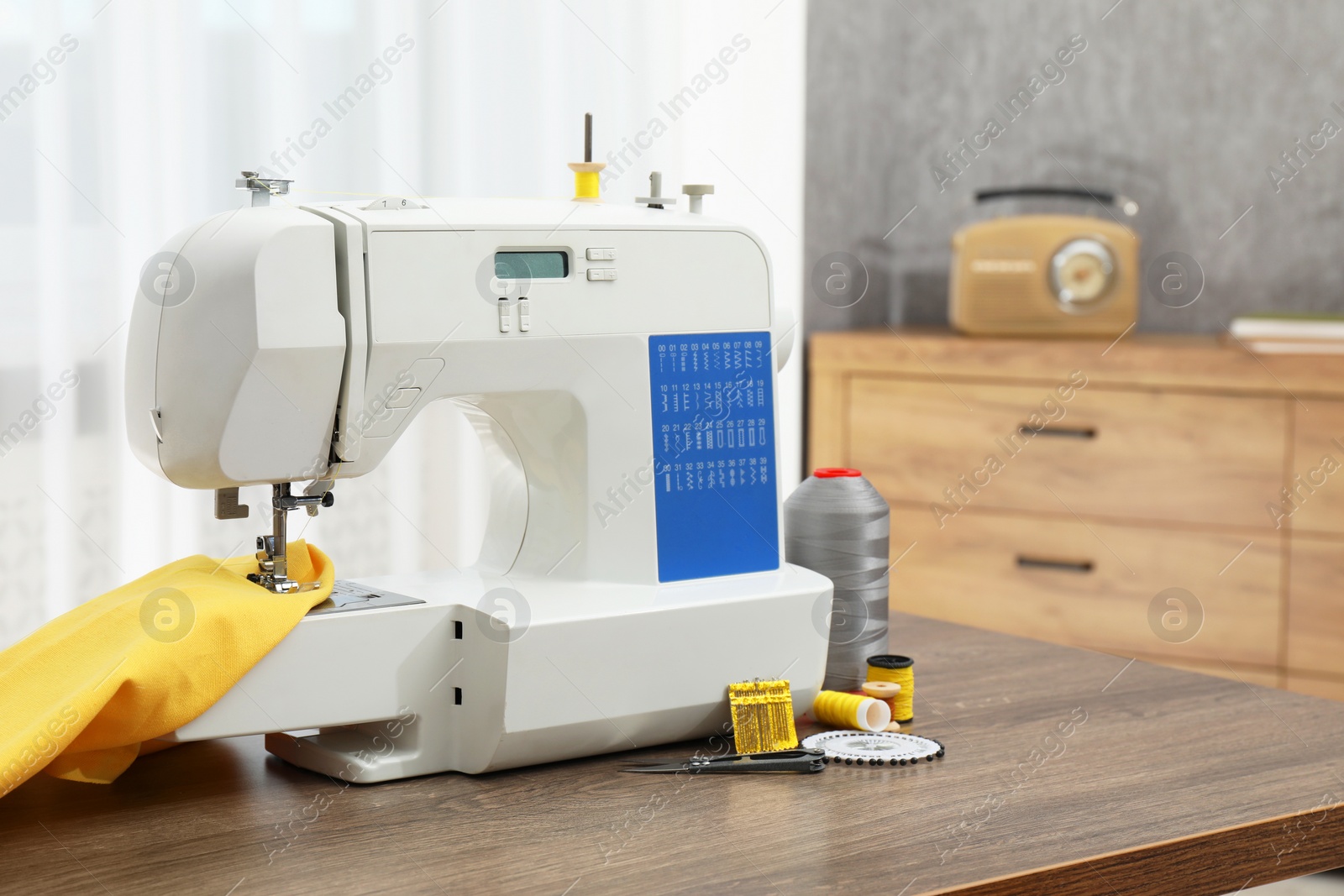 Photo of Sewing machine with fabric and craft accessories on wooden table indoors