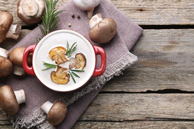 Photo of Delicious homemade mushroom soup in ceramic pot and fresh ingredients on wooden table, flat lay. Space for text