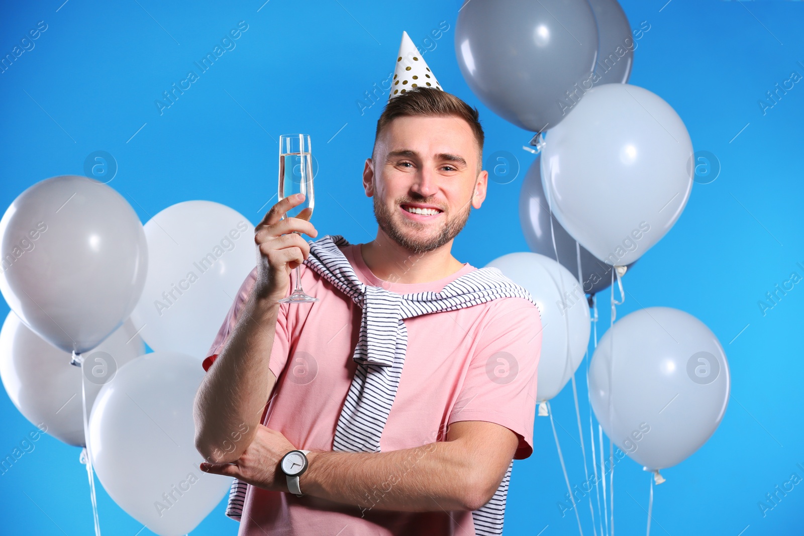 Photo of Portrait of happy man with champagne in glass and party balloons on color background