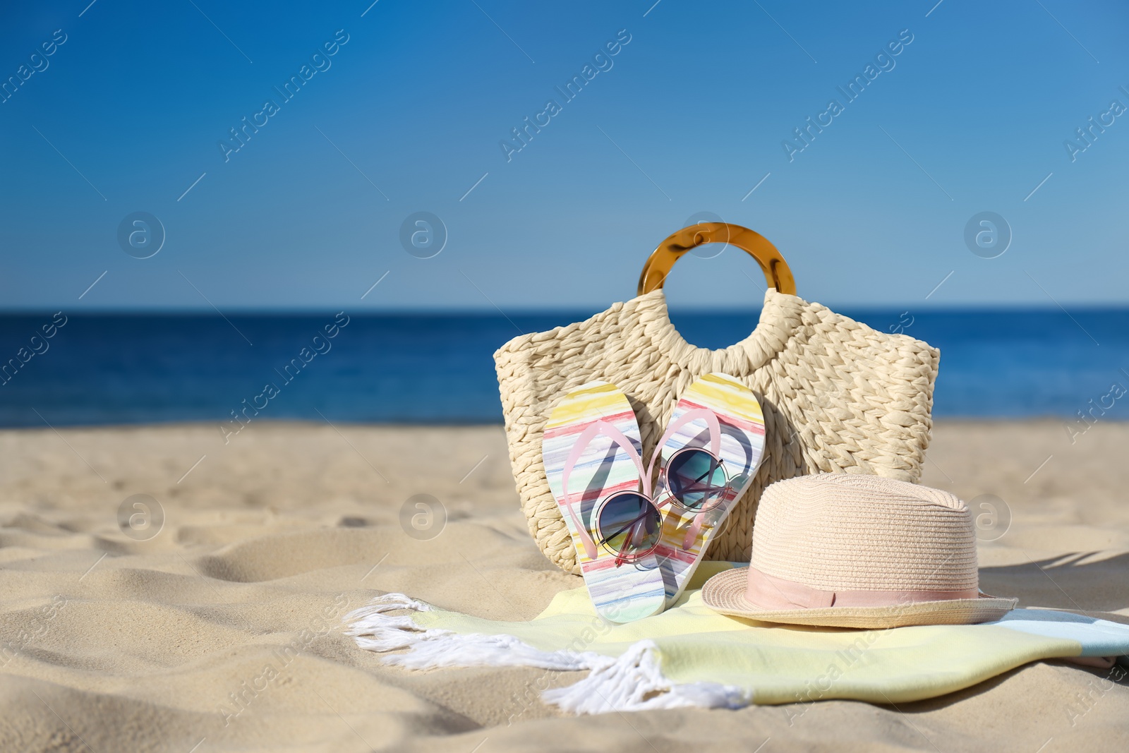 Photo of Stylish beach accessories for summer vacation on sand near sea. Space for text