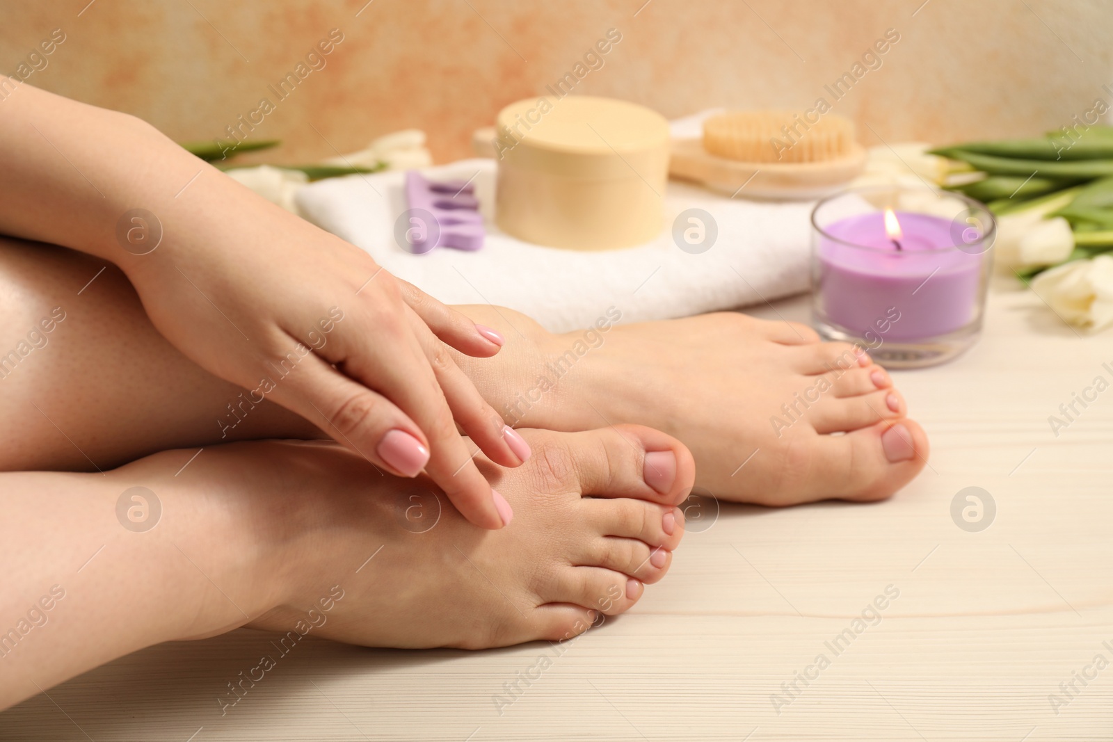 Photo of Woman with neat toenails after pedicure procedure on wooden floor, closeup