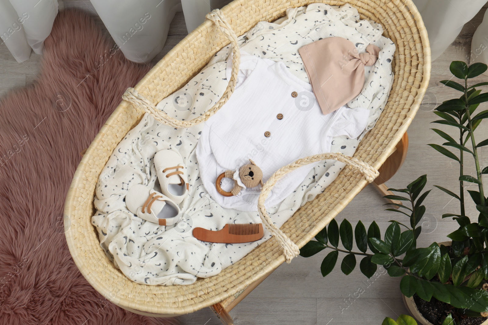 Photo of Cute baby clothes and accessories in basket bassinet at home, top view