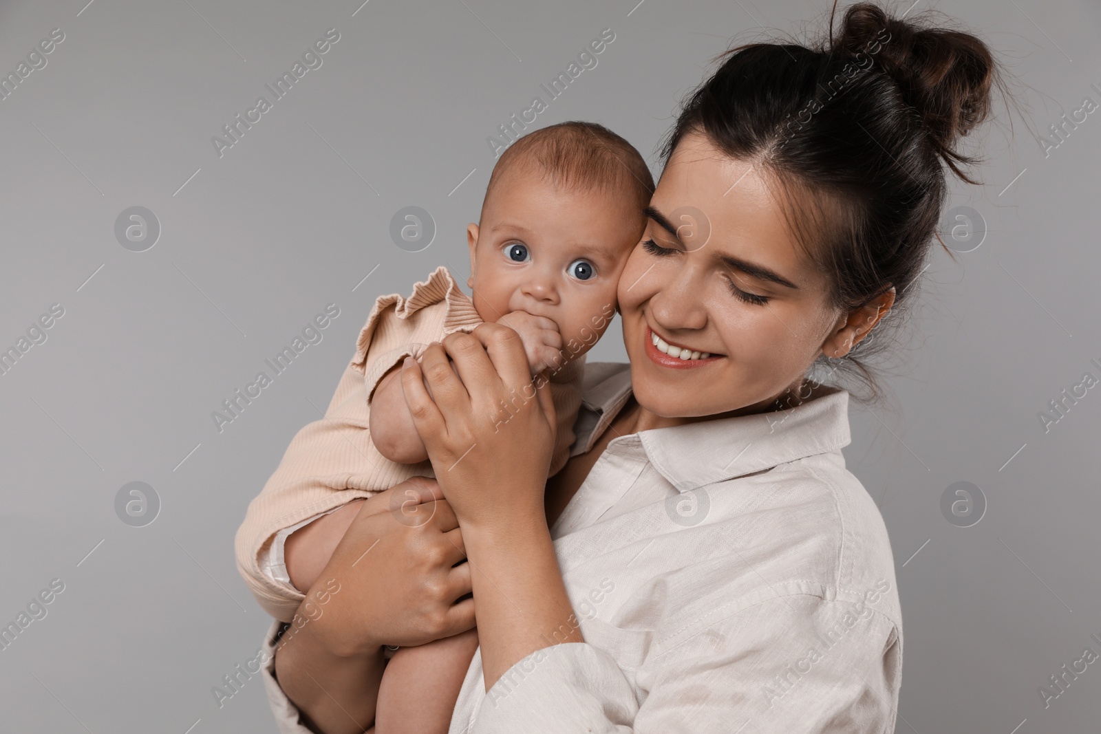 Photo of Beautiful mother with her cute baby on grey background