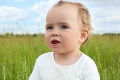 Photo of Portrait of adorable little baby in green field
