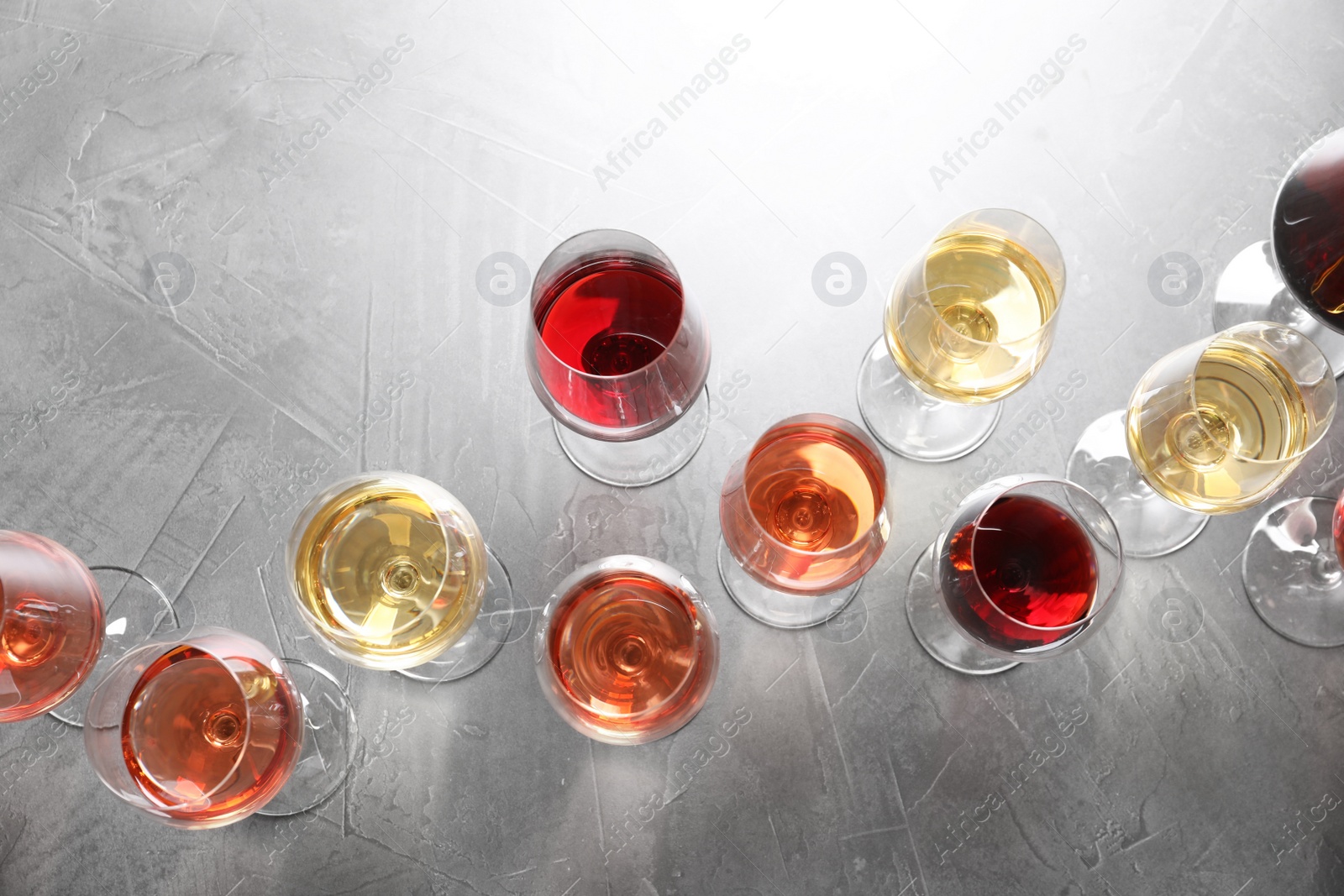 Photo of Different glasses with wine on grey background, flat lay