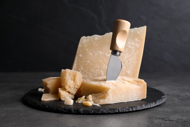 Photo of Parmesan cheese with knife on grey table