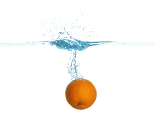 Ripe orange falling down into clear water with splashes against white background