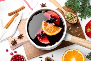 Delicious mulled wine and ingredients on white table, flat lay